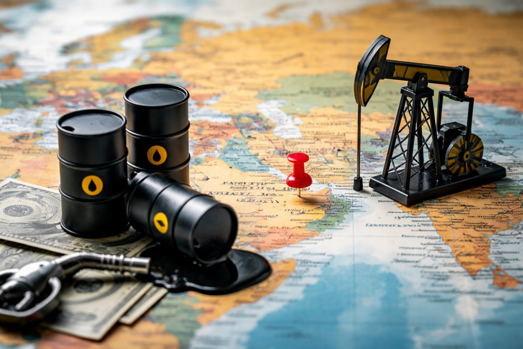 Des barils de pétrole, une maquette de pompe à balancier et des billets de banque placés sur une carte du monde illustrent la relation entre la géopolitique et les marchés pétroliers.