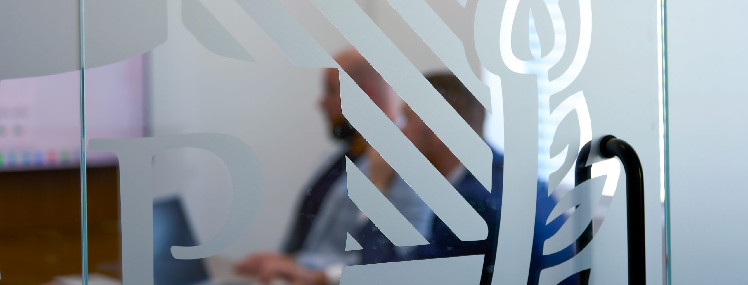 Pérennité office — logo etched on a meeting-room glass wall